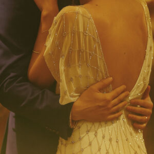 A couple dancing at a wedding, featuring a bespoke beaded after-party wedding dress with an open back.
